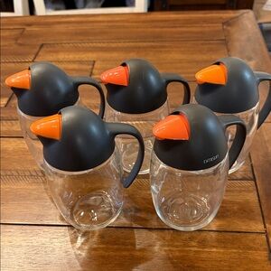 Penguin-shaped glass oil and vinegar dispensers with automatic flip caps.
